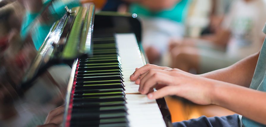 Aluno praticando aulas de piano na canto do batuque | Escola de música em SP