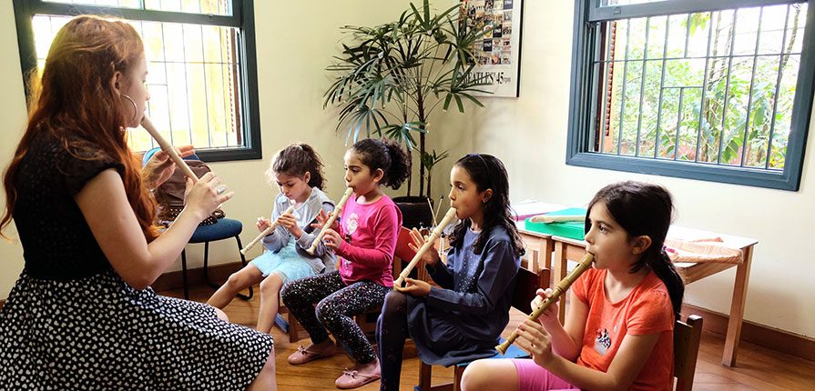 Professora de musicalização infantil praticando aulas de flauta com as crianças